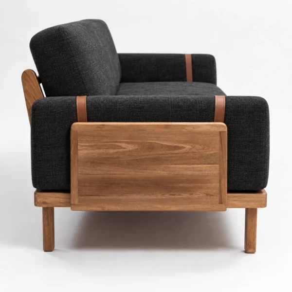 Costado del Sofá Juan: panel lateral en madera maciza y correas de cuero sobre tapizado Charcoal